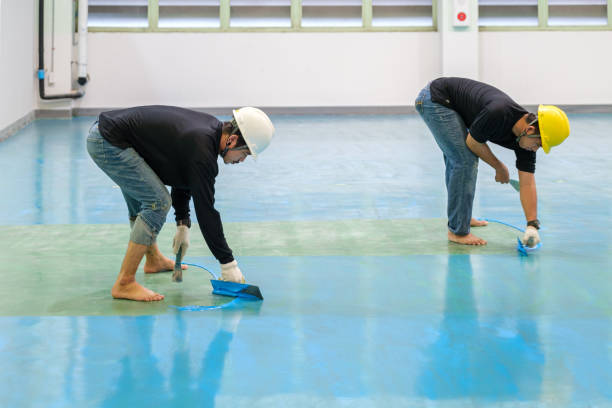 Two men installing and smoothing epoxy flooring in Norwalk.